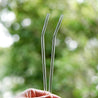hands holding two bendy glass straws during the day outdoors